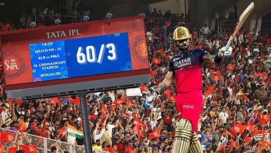 Cricket player in pink uniform hits a six during IPL match, with cheering crowd and scoreboard in backgro.