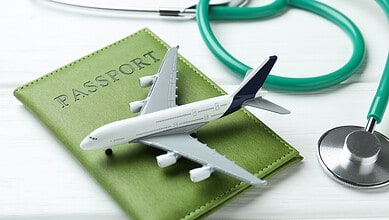 Travel and medical tourism essentials with airplane, passport, and stethoscope.