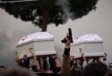 A gunman fires his gun as men carry the coffins with the bodies of Pierre Mouawad, an official with the anti-Hezbollah Lebanese Forces party, and his wife during their funeral in Yahshush, in Lebanon on Tuesday, April 7.
