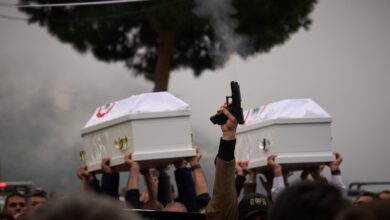 A gunman fires his gun as men carry the coffins with the bodies of Pierre Mouawad, an official with the anti-Hezbollah Lebanese Forces party, and his wife during their funeral in Yahshush, in Lebanon on Tuesday, April 7.