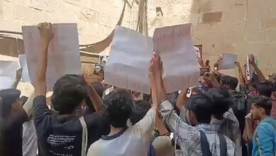 Students protesting RSS 100-year celebration at Jamia campus, security personnel present.