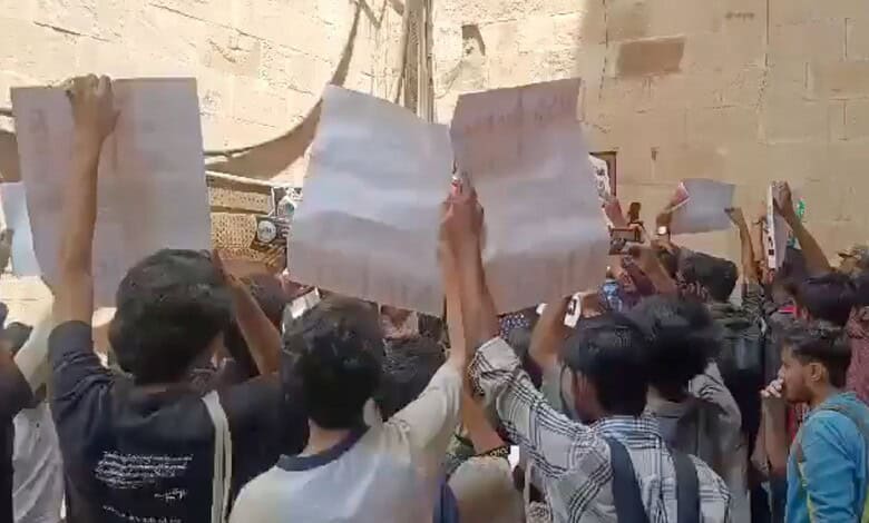 Students protesting RSS 100-year celebration at Jamia campus, security personnel present.