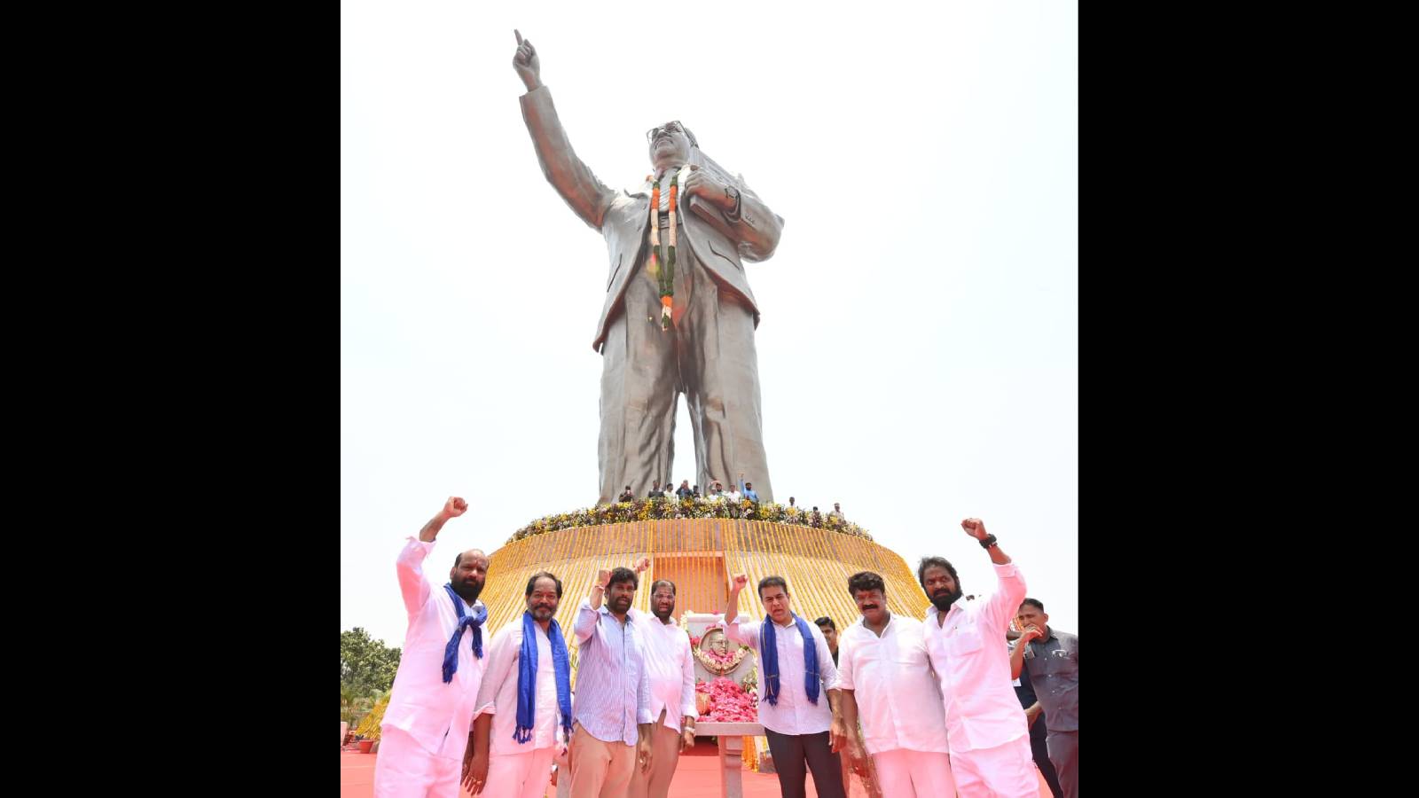 Group of people paying tribute at the Ambedkar statue in Hyderabad, highlighting respect through deeds.