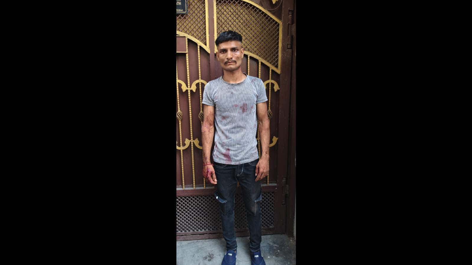 Man standing outside a gate in Hyderabad, wearing a grey t-shirt and jeans, related to a family dispute i.