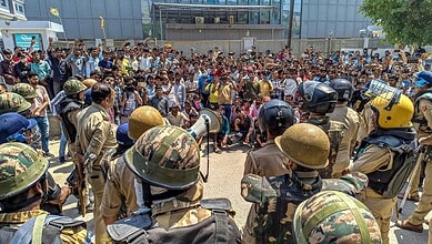 Security personnel stand guard as factory workers stage a protest demanding a hike in wages, in Noida, Gautam Buddh Nagar district, Uttar Pradesh, on April 13. The protest carried incidents of arson, vandalism and stone-pelting reported from Phase-2 and Sector 60 areas, police said.
