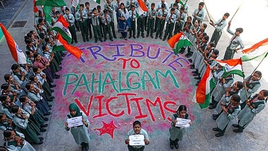 A large group of students and community members gather in a circle holding flags and signs, paying tribute to Pahalgam attack victims.