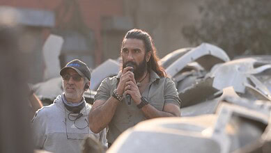 BTS image of Dhurandhar speaking into a microphone on set of his upcoming film.