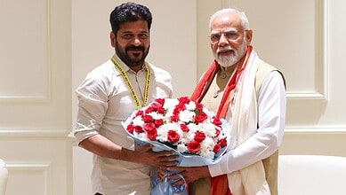 Telangana Chief Minister with Prime Minister Modi exchanging a flower bouquet during a meeting.
