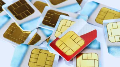 Image shows A pile of SIM cards with gold chips, one featuring a distinctive red design, scattered on a white surface.