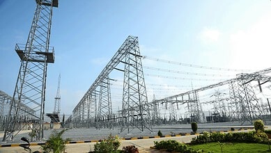 Power transmission towers and high-voltage lines at an electrical substation.