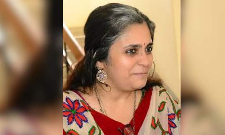 Indian woman in traditional attire with earrings, looking to the side, indoors.