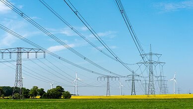Power transmission towers and wind turbines in Telangana, highlighting new energy infrastructure.