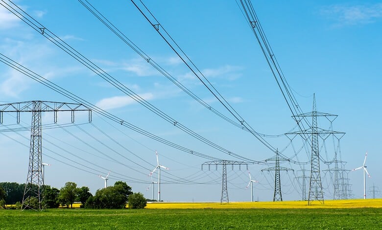 Power transmission towers and wind turbines in Telangana, highlighting new energy infrastructure.