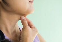 Woman touching her neck showing a painless lump, highlighting importance of medical check for neck swelli.