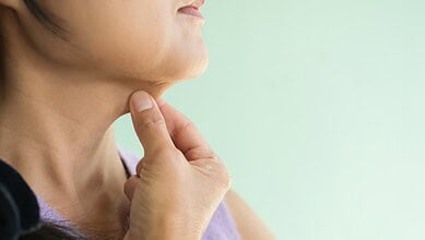 Woman touching her neck showing a painless lump, highlighting importance of medical check for neck swelli.