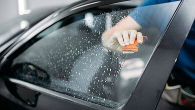 Officer cleaning car window as part of Hyderabad crackdown on tinted glass and black films.