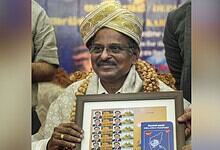 Indian scientist holding framed ISRO-related artwork at event.
