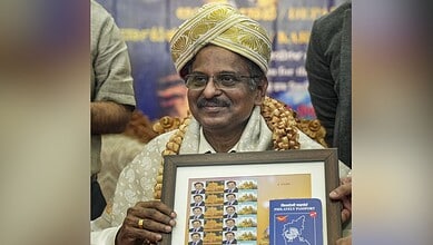 Indian scientist holding framed ISRO-related artwork at event.