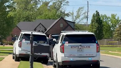 Police vehicles at the crime scene with officers investigating.
