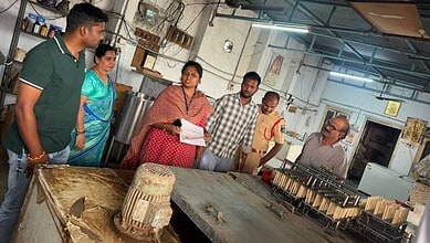 People inspecting sweets in a bakery workshop with large containers and equipment.