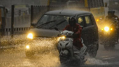 Rainy weather in Hyderabad with vehicles and pedestrians dealing with evening rains.