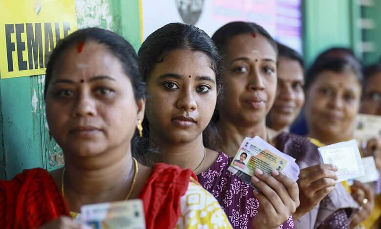 Women holding voter ID cards during election in West Bengal and Tamil Nadu.