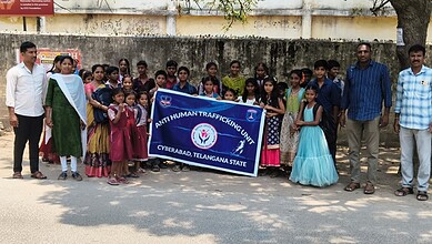 Group of children and officials holding a banner during Cyberabad decoy operation in Telangana.