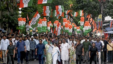 Crowd of supporters at a political rally with BJP flags and orange, white, green balloons in India.