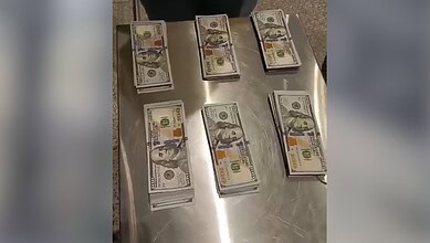 Seized US dollar bundles displayed on a table at Hyderabad Airport security.