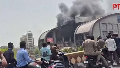 Large fire engulfs Kota's City Mall with thick black smoke, people watch as emergency services respond.