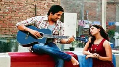 Yami Gautam playing guitar on set, smiling at co-star in a casual outdoor scene.