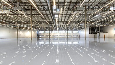 Industrial warehouse interior with high ceilings, metal beams, and polished concrete floor for leasing op.