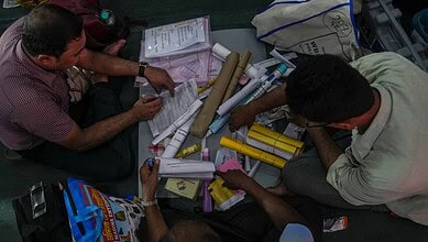 Two men examining documents and posters related to election troublemakers in Calcutta.