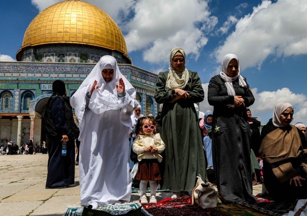 Palestinian women and a child pray at Al-Aqsa Mosque compound in Jerusalem after reopening.
