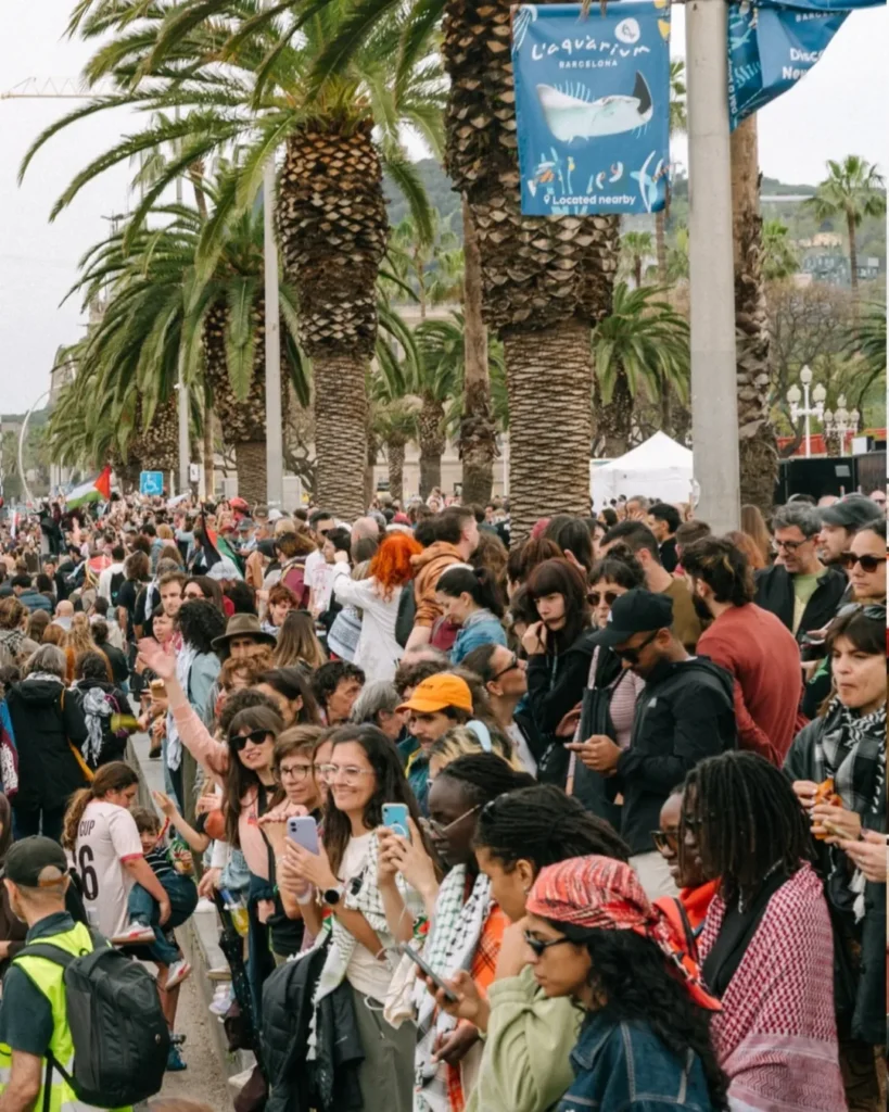Large crowd gathers near Barcelona port during flotilla departure.