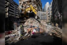Excavator clearing debris at damaged building after strikes in Beirut