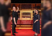 Big Ticket Abu Dhabi hosts Richard and Bouchra Yamani stand beside the raffle draw machine on stage.