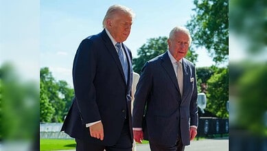 US President Donald Trump walks beside King Charles III outdoors during an official meeting in sunny surroundings.