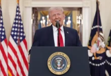US President Donald Trump delivers a speech at a podium with American flags in the background.