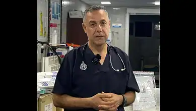 Emergency medical professional in hospital setting, wearing scrubs and stethoscope, preparing for patient.