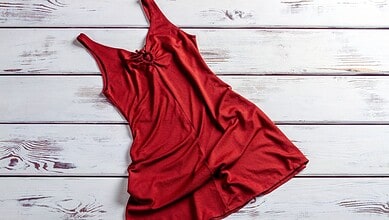 A stylish red dress displayed on a white wooden background, highlighting online dress shopping scams and the importance of secure transactions.