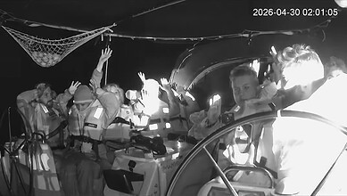 Activists aboard Gaza-bound flotilla vessel raise hands during interception at sea.