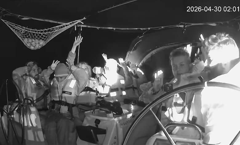 Activists aboard Gaza-bound flotilla vessel raise hands during interception at sea.