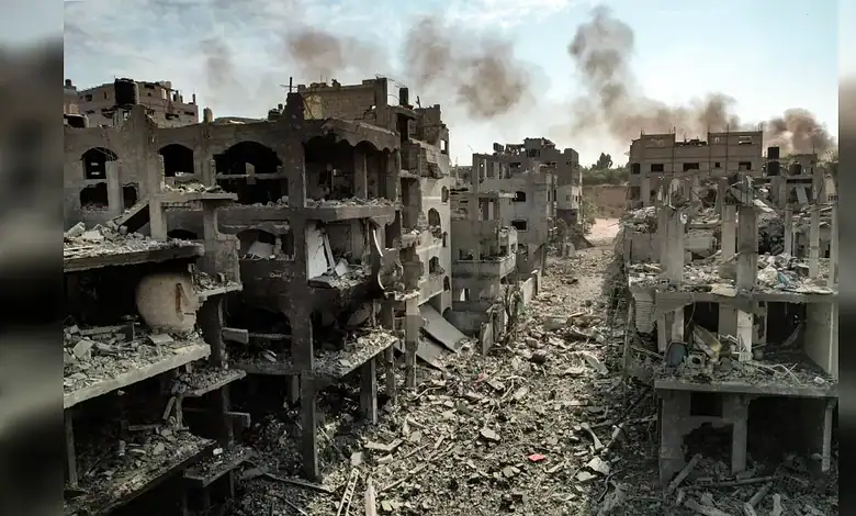 Ruined buildings and debris in a conflict zone, with smoke rising in the background.