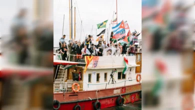 Activists wave flags aboard a flotilla vessel departing Barcelona port