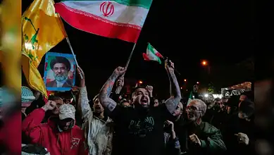 Iranian crowds celebrate ceasefire on April 8, waving national flags and holding a portrait of the Supreme Leader during a nighttime rally in Tehran.