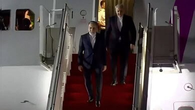 Iranian Foreign Minister Araghchi walking down the stairs in formal attire in Islamabad.
