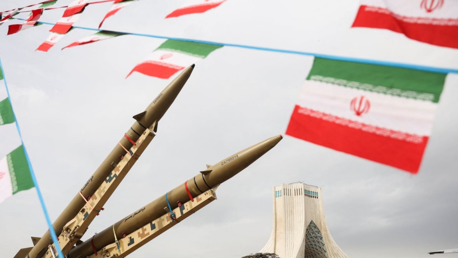 Iranian missiles on display with national flags in the background.