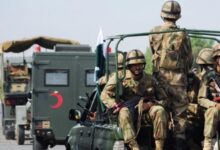 Pakistani army soldiers in uniform seated on a military vehicle during deployment.