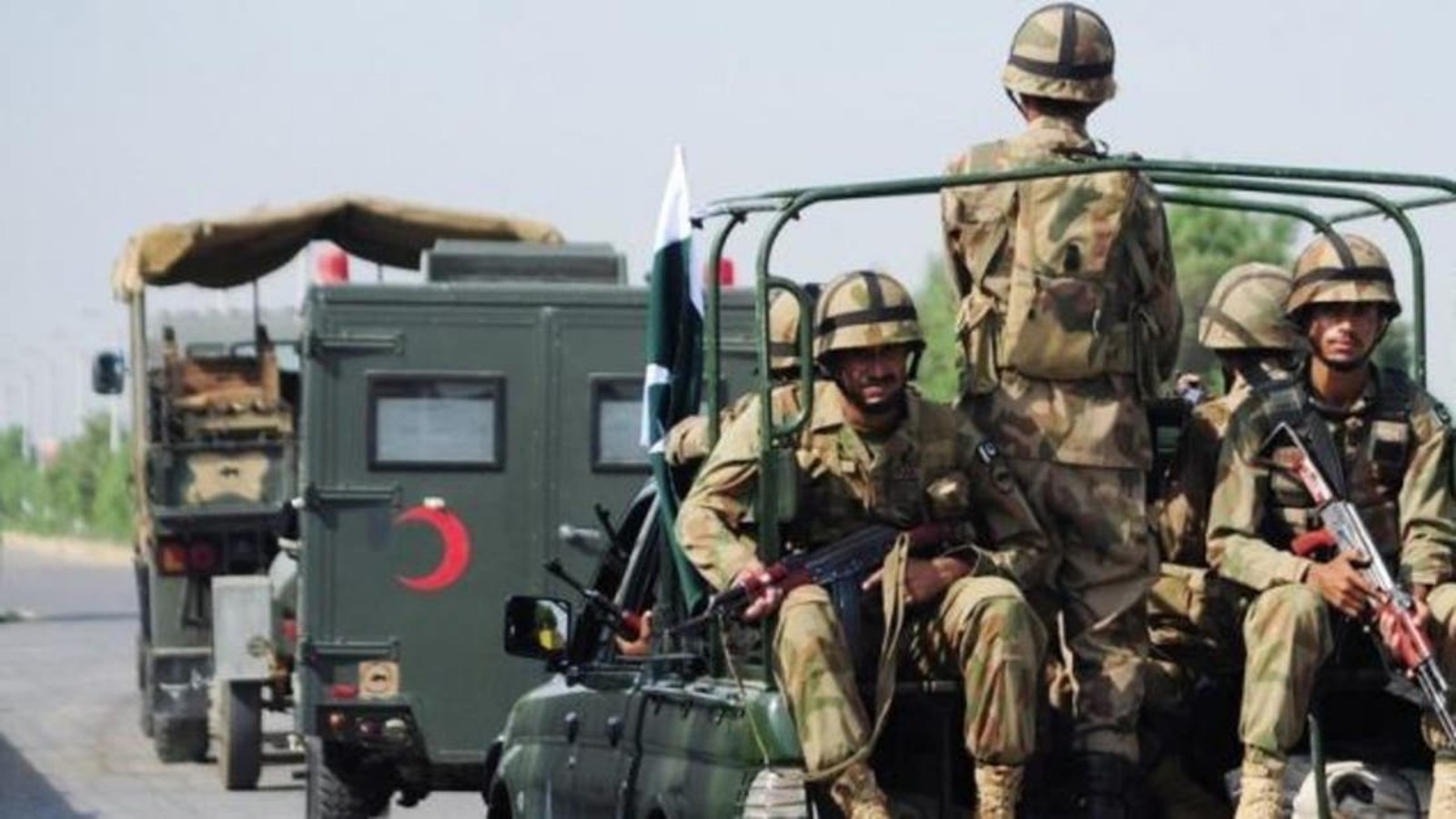 Pakistani army soldiers in uniform seated on a military vehicle during deployment.